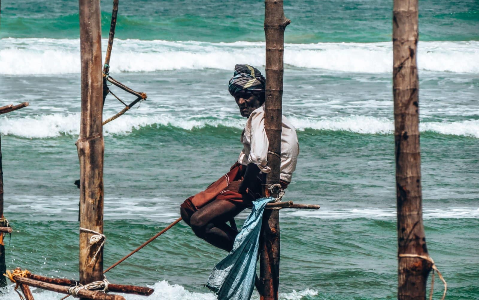 Fisherman perched on small bamboo pole in the Indian Ocean